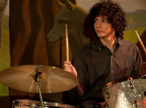 A picture of John Magaro playing drums in the movie 'Not Fade Away'.
